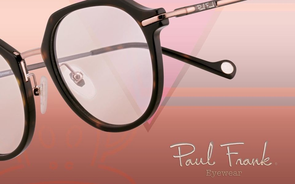 A close-up image of a pair of black-rimmed Paul Frank eyeglasses against a pink gradient background.